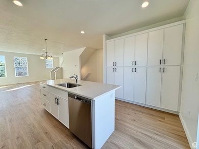 Kitchen featuring white cabinetry, pendant lighting, stainless steel dishwasher, recessed lighting, and light wood finished floors