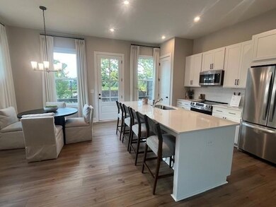 Kitchen with stainless steel appliances, white cabinetry, an island with sink, a breakfast bar area, and healthy amount of natural light