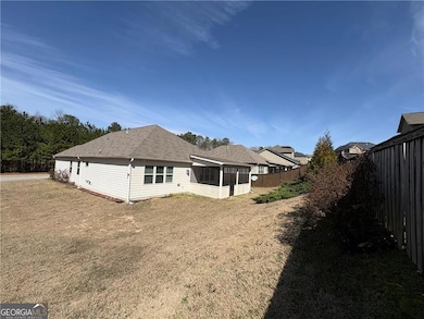 Back of house featuring a sunroom and roof with shingles