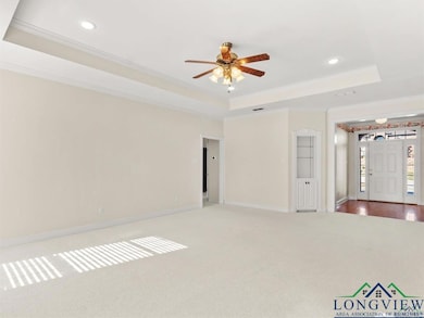 Unfurnished living room with a raised ceiling, carpet floors, ornamental molding, a ceiling fan, and recessed lighting