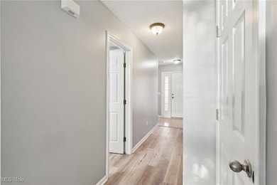Corridor with a textured ceiling and light wood-style floors