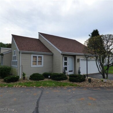 View of front of house featuring asphalt driveway, roof with shingles, and an attached garage