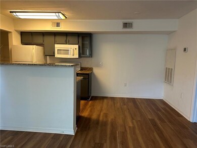 Kitchen featuring white appliances, dark hardwood / wood-style floors, and dark stone countertops