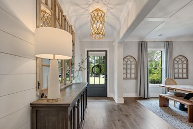 Entryway featuring dark wood-style flooring, a chandelier, baseboards, and crown molding