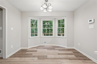 Unfurnished dining area featuring healthy amount of natural light, a chandelier, light wood-style floors, and a textured ceiling
