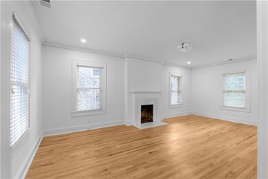 Unfurnished living room featuring ornamental molding, plenty of natural light, light wood finished floors, a fireplace, and baseboards