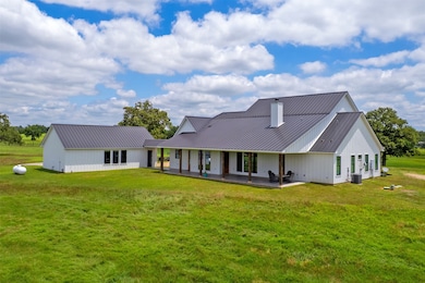 Rear view of house with a lawn, metal roof, and a patio
