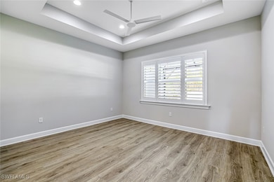 Spare room featuring a tray ceiling, wood finished floors, ceiling fan, and recessed lighting