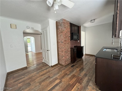 Kitchen with sink, Dining Area with wood-style flooring, dark brown cabinetry, a textured ceiling, and ceiling fan
