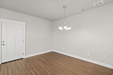 Unfurnished room featuring dark wood finished floors and a chandelier
