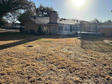 Back of house with a lawn, a chimney, roof with sh