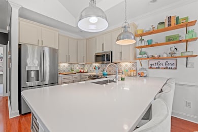 Kitchen with appliances with stainless steel finishes, a peninsula, crown molding, wood finished floors, and tasteful backsplash