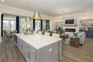 Kitchen featuring ornamental molding, a center island, a glass covered fireplace, wood finished floors, and light countertops