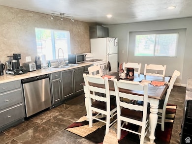 Kitchen with appliances with stainless steel finishes, plenty of natural light, and gray cabinets