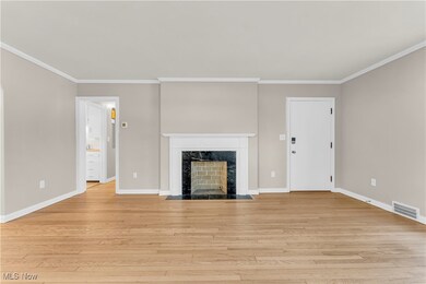 Unfurnished living room with ornamental molding, a high end fireplace, and light hardwood / wood-style floors