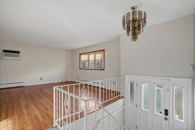 Entryway with light wood-style floors, a wall mounted air conditioner, and a baseboard heating unit
