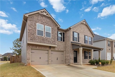 View of front of house with a porch, an attached garage, concrete driveway, and brick siding