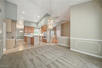 Kitchen featuring a chandelier, pendant lighting, light tile patterned flooring, light countertops, and light carpet