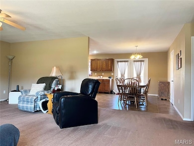 Living room with light carpet, light tile patterned flooring, a chandelier, and ceiling fan