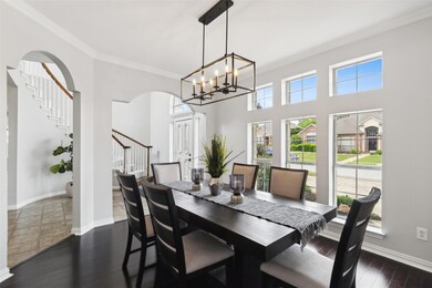 Dining room with dark tile flooring, a notable chandelier, a high ceiling, and ornamental molding
