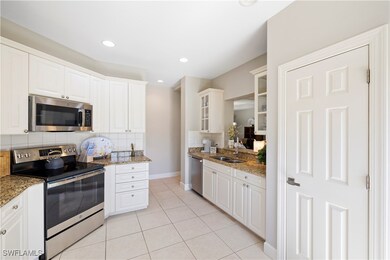 Kitchen featuring stainless steel appliances, glass insert cabinets, light tile patterned floors, white cabinets, and tasteful backsplash