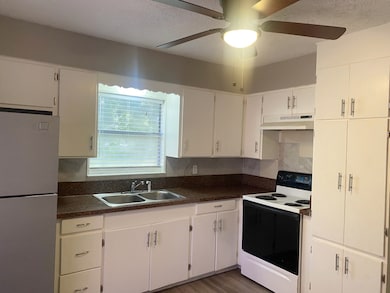 Kitchen featuring electric stove, freestanding refrigerator, dark countertops, a textured ceiling, and white cabinets