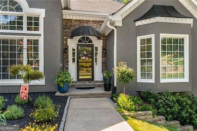 Entrance to property featuring stone siding, stucco siding, and a shingled roof