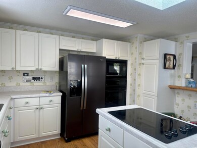 Kitchen with a textured ceiling, light hardwood / 