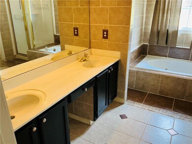Bathroom featuring double vanity, a tub with jets, tile patterned floors, and tile walls