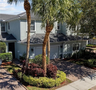 View of front of house featuring a garage, a tile roof, stucco siding, and decorative driveway