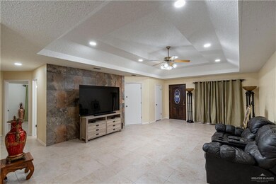 Living room with a tray ceiling, a ceiling fan, light tile patterned floors, recessed lighting, and a textured ceiling