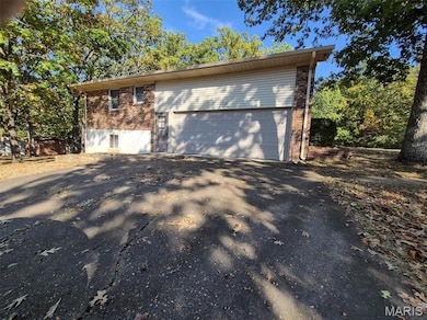 View of property exterior featuring a garage, driveway, and brick siding