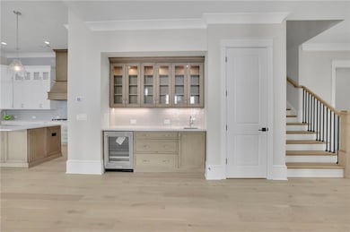 Bar with crown molding, stairs, premium range hood