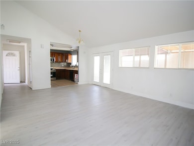 Unfurnished living room featuring light wood-style floors, baseboards, and high vaulted ceiling