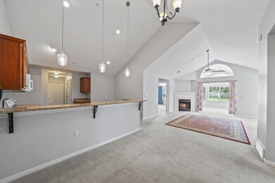 featuring lofted ceiling, carpet, brown cabinets, pendant lighting, and a fireplace
