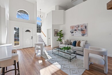 Living room with a high ceiling, light hardwood / 