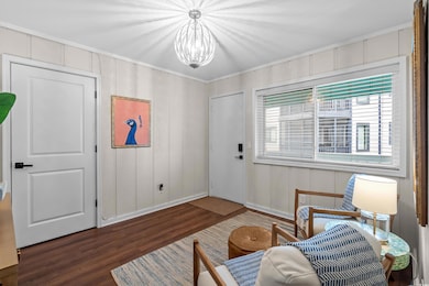 Sitting room with wood finished floors, a chandelier, crown molding, and baseboards