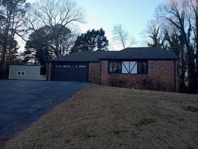 View of front facade featuring a carport, a garage, and a front yard