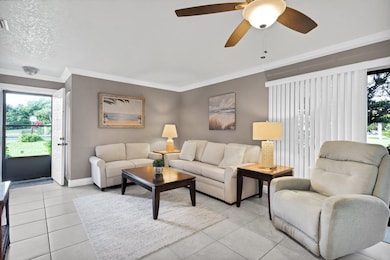 Living room with tile patterned flooring, crown molding, and a ceiling fan