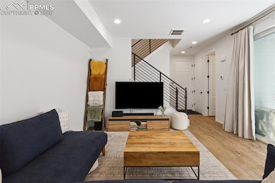 Living area with stairs, access to covered patio, Luxury Vinyl Tile flooring, and recessed lighting