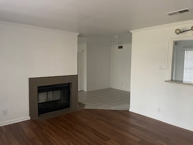 Unfurnished living room featuring dark wood-style floors, a fireplace with flush hearth, and ornamental molding