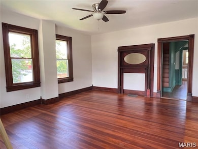 Unfurnished room featuring dark wood-style floors, plenty of natural light, and ceiling fan