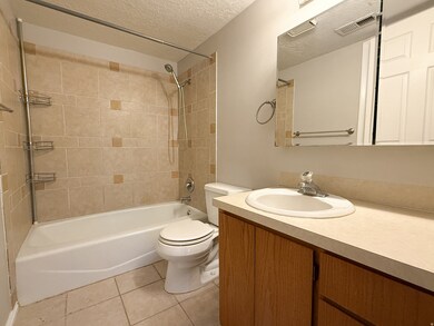 Full bathroom featuring a textured ceiling, light tile patterned flooring, tub / shower combination, and vanity