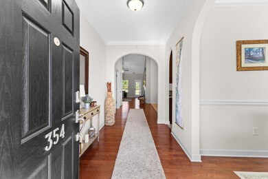 Hallway with ornamental molding and dark hardwood 