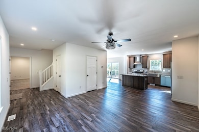 Kitchen with dark brown cabinetry, recessed lighting, open floor plan, a kitchen island, and dark wood-type flooring