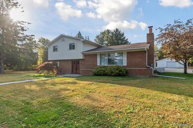 Tri-level home with a chimney, a front lawn, and brick siding