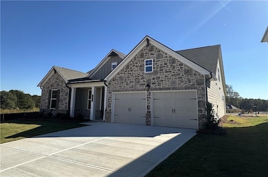 View of front of house featuring a front lawn, stone siding, concrete driveway, and a garage