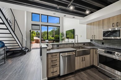 Kitchen with stainless steel appliances, rail lighting, dark countertops, dark wood-style flooring, and a peninsula