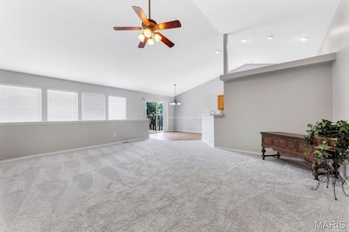 Carpeted living room with a ceiling fan and lofted ceiling