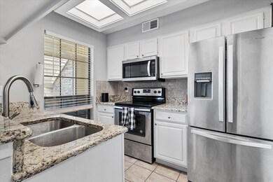Kitchen with white cabinetry, light stone countert